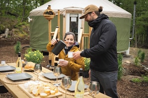 A tent with a table set for a meal, including cheese, wine, and bread. - Cozy Yurt in the Woods (Sainte-Agathe-des-Monts)