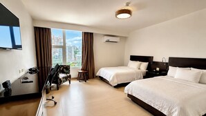 Habitación de hotel con dos camas, un escritorio, una silla y un televisor.