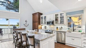 Una cocina moderna con armarios blancos, encimera de granito y un área de comedor con taburetes de bar.