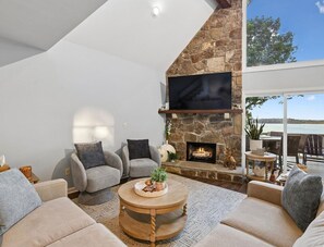 Un salon moderne avec une cheminée en pierre, des sièges confortables et un grand téléviseur.