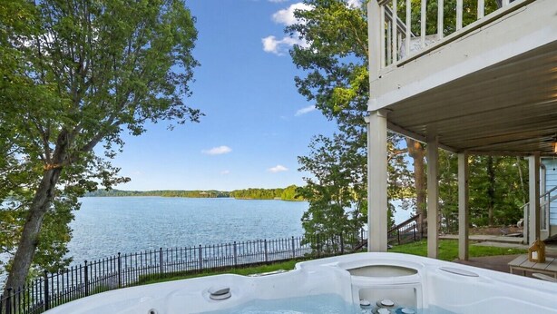 Un jacuzzi con vista al lago, una terraza y una barandilla.