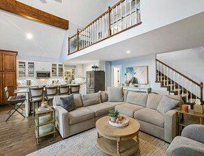 A spacious living area with a large sectional sofa, a coffee table, and a dining area with chairs and a kitchen in the background. - Sunrise Point Lakehouse (Winchester)
