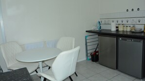 A kitchen with a white table and chairs, a dishwasher, and a tiled backsplash. - Whole Cosy Home, Sleeps 11 in 4 Bedrooms, full kitchen, 2 toilets, 55"TVs PetsOK (Wolverhampton)