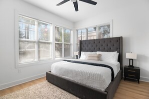 Ein Schlafzimmer mit einem großen Bett, einem Deckenventilator und einem Nachttisch mit Lampe.