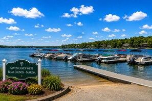 Ein Yachthafen mit vertäuten Booten, ein Schild mit der Aufschrift 'Seven Lakes West Boat Launch - Marina' und ein klarer, blauer Himmel.