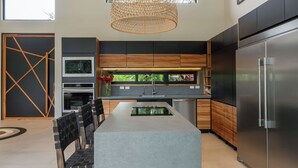 Uma cozinha moderna com ilha central, eletrodomésticos de aço inoxidável e uma janela grande.