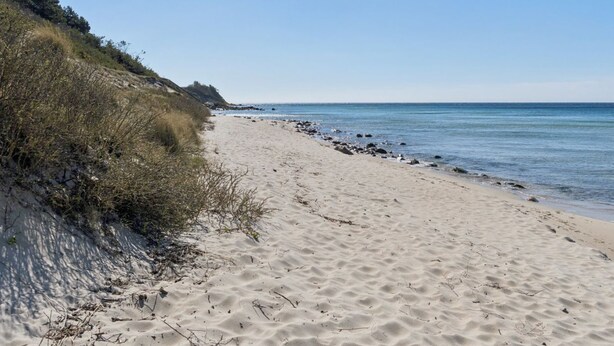 A sandy beach with a gentle slope leading to the water, a clear sky, and a distant shoreline. - "Mirzə" - 180m from the sea by Interhome (Rønne)