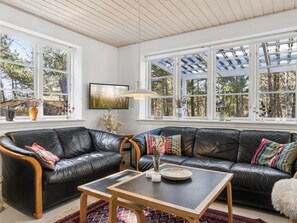 Ein Wohnzimmer mit einer schwarzen Ledersofa, einem Holztisch und einem an der Wand befestigten Fernseher.