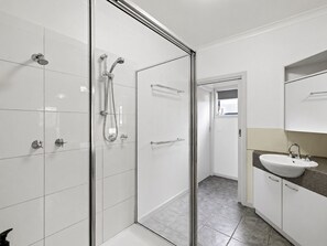 A modern bathroom with a glass shower enclosure, a sink with a countertop, and a mirror above the sink.