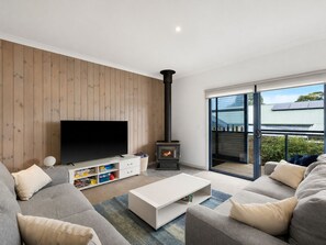 A modern living room with a flat-screen TV, a built-in fireplace, and a sliding glass door to a balcony.