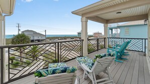 Ein Balkon mit weißen Stühlen und Blick auf den Strand.