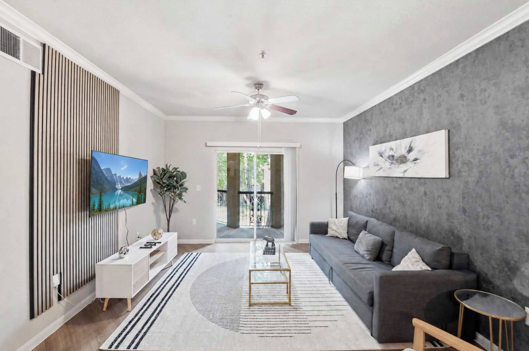 A modern living room with a sofa, TV, and decorative items.