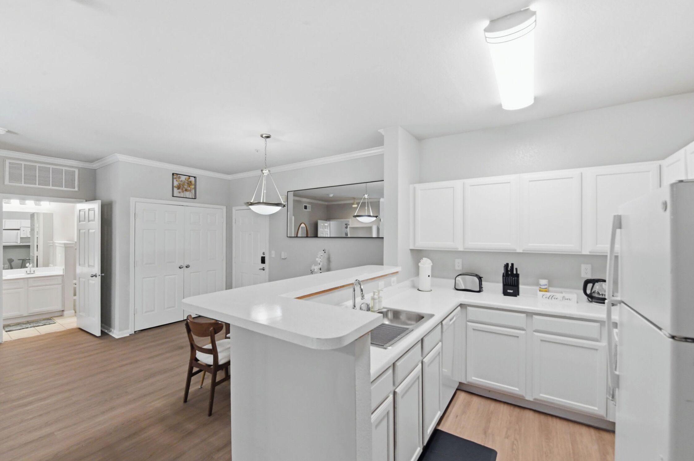 Una cocina moderna con armarios blancos, una isla central e iluminación colgante.