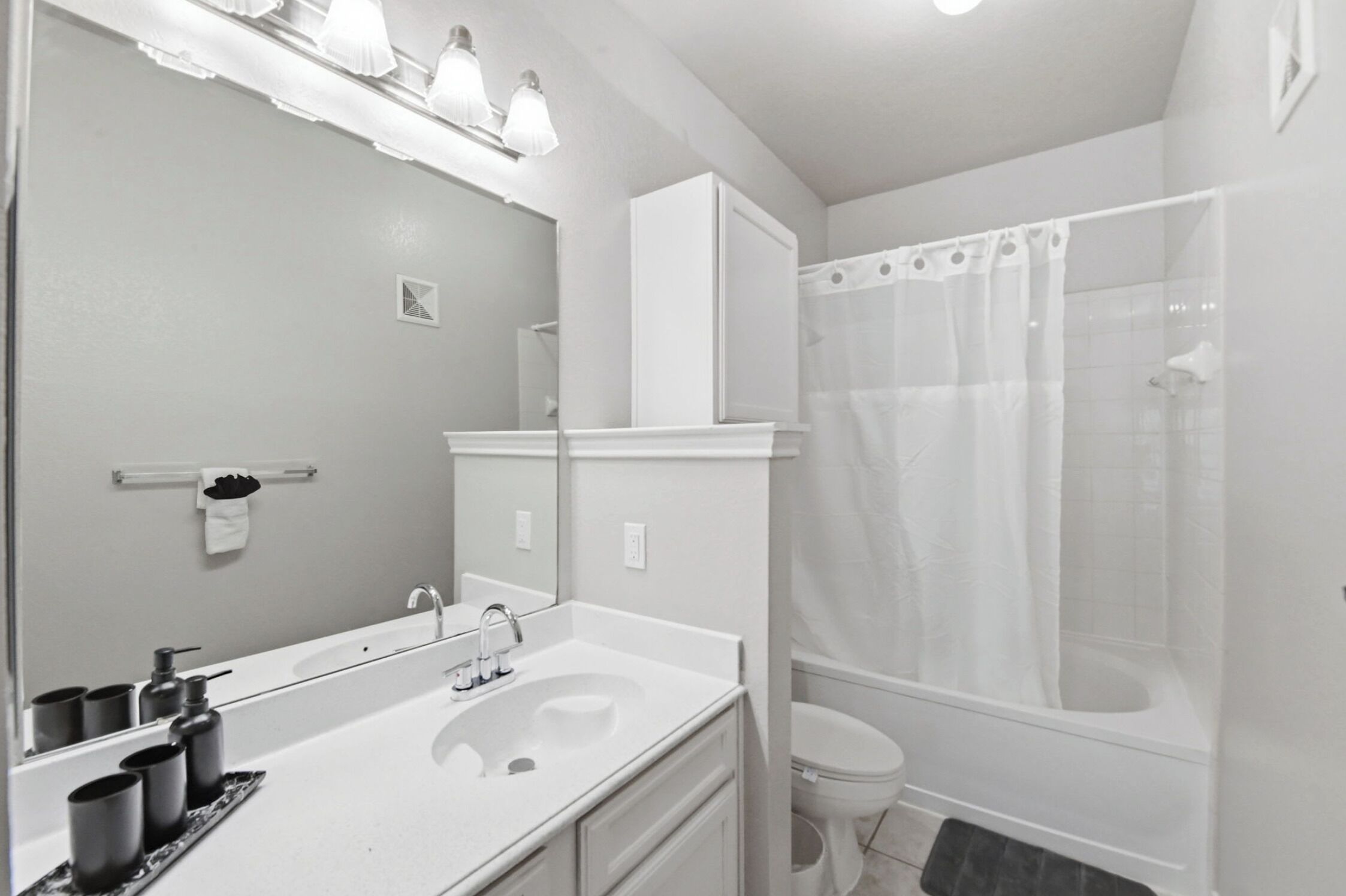 A bathroom with a sink, mirror, toilet, and shower.