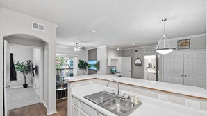A modern kitchen with white cabinetry, a stainless steel sink, and a ceiling fan. -  Inwoods Park by Stylish Stays (Dallas)