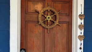 Een houten deur met een decoratieve stuurrad en een brievenbus.