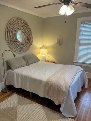 Un dormitorio con cama, lámpara de noche, decoración en la pared y ventilador de techo.