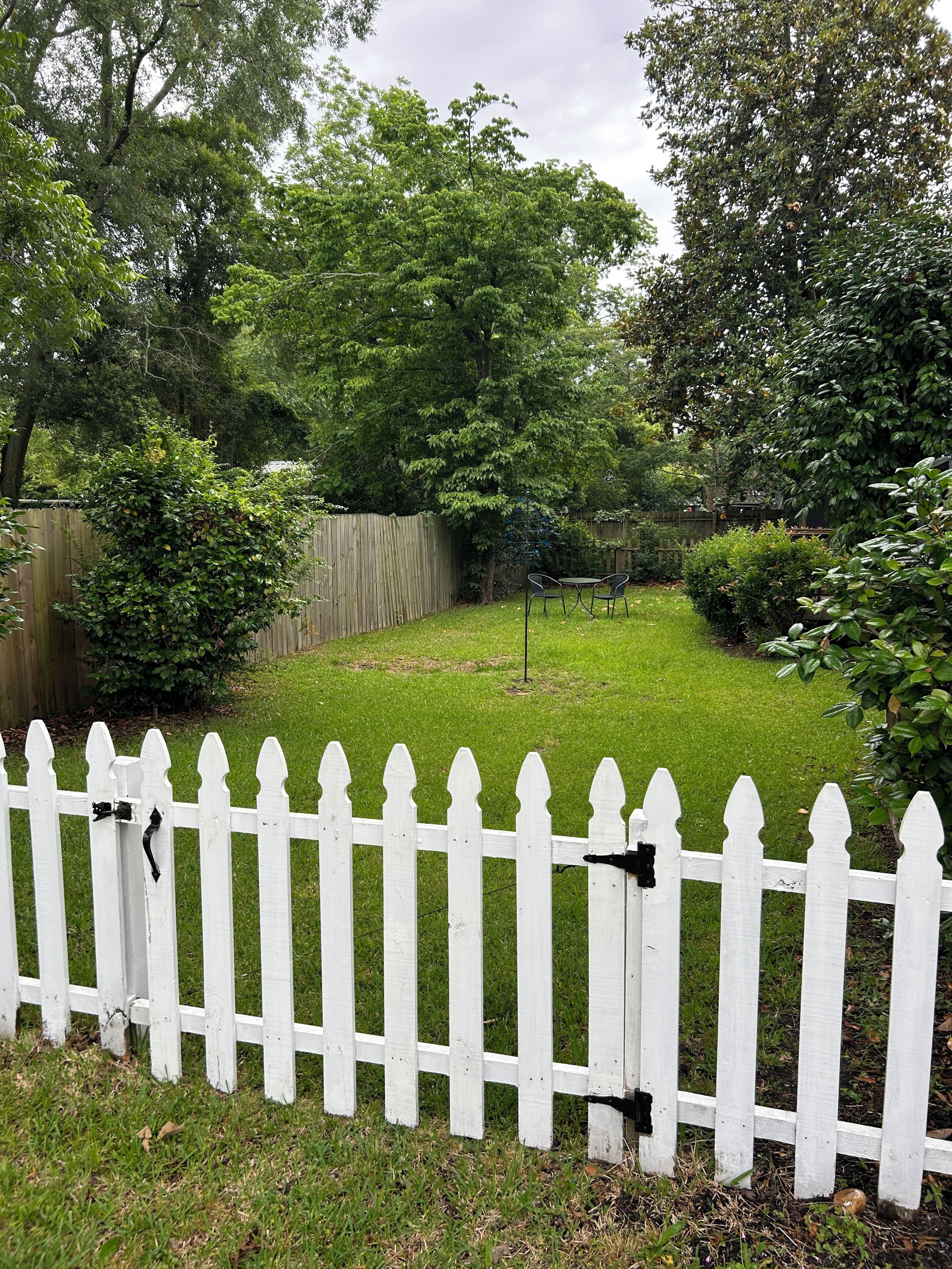 Ein umzäunter Garten mit Rasen, Bäumen und einem Holzzaun.