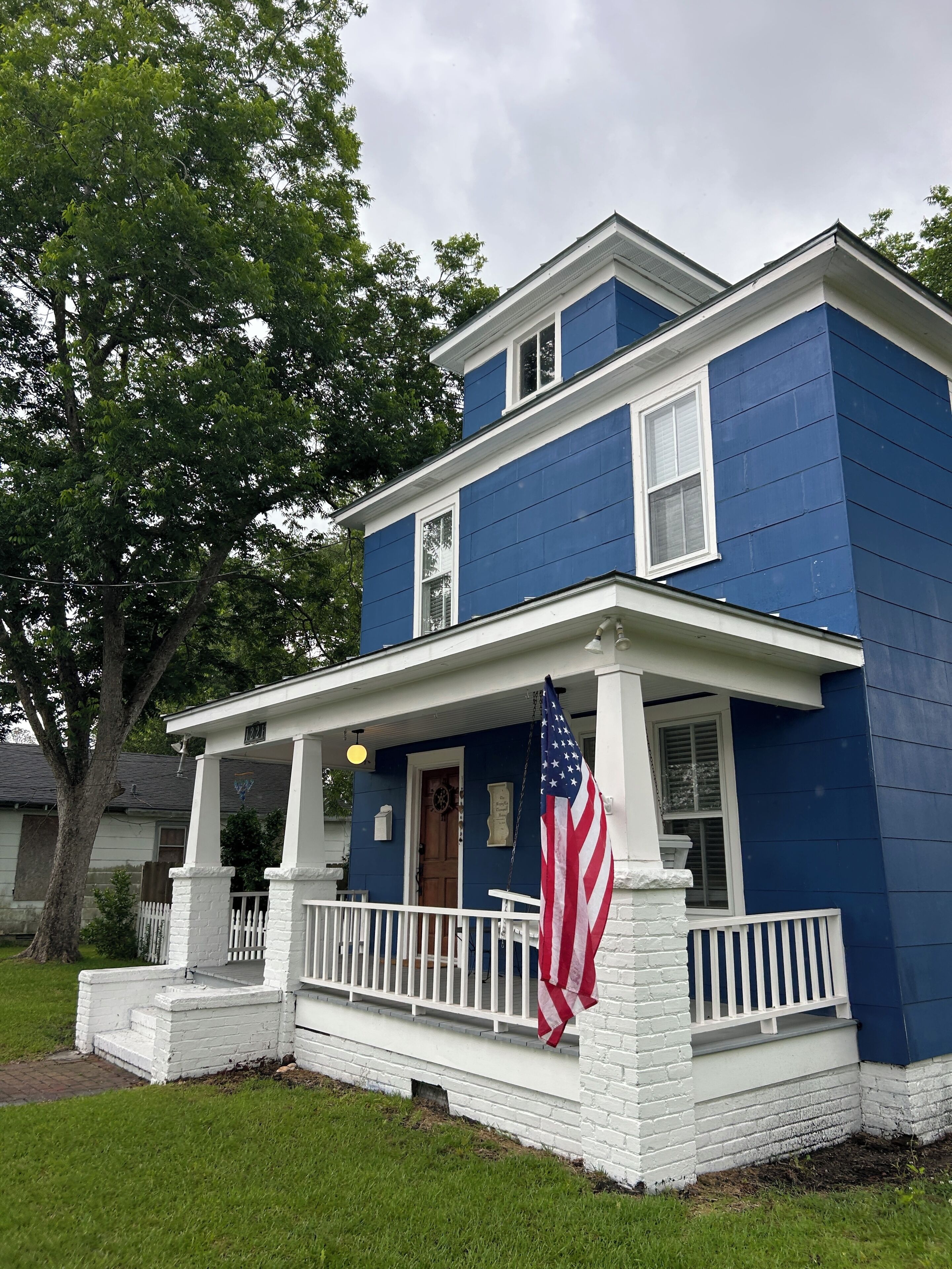 Et toetagers hus med veranda, et amerikansk flag og en postkasse.