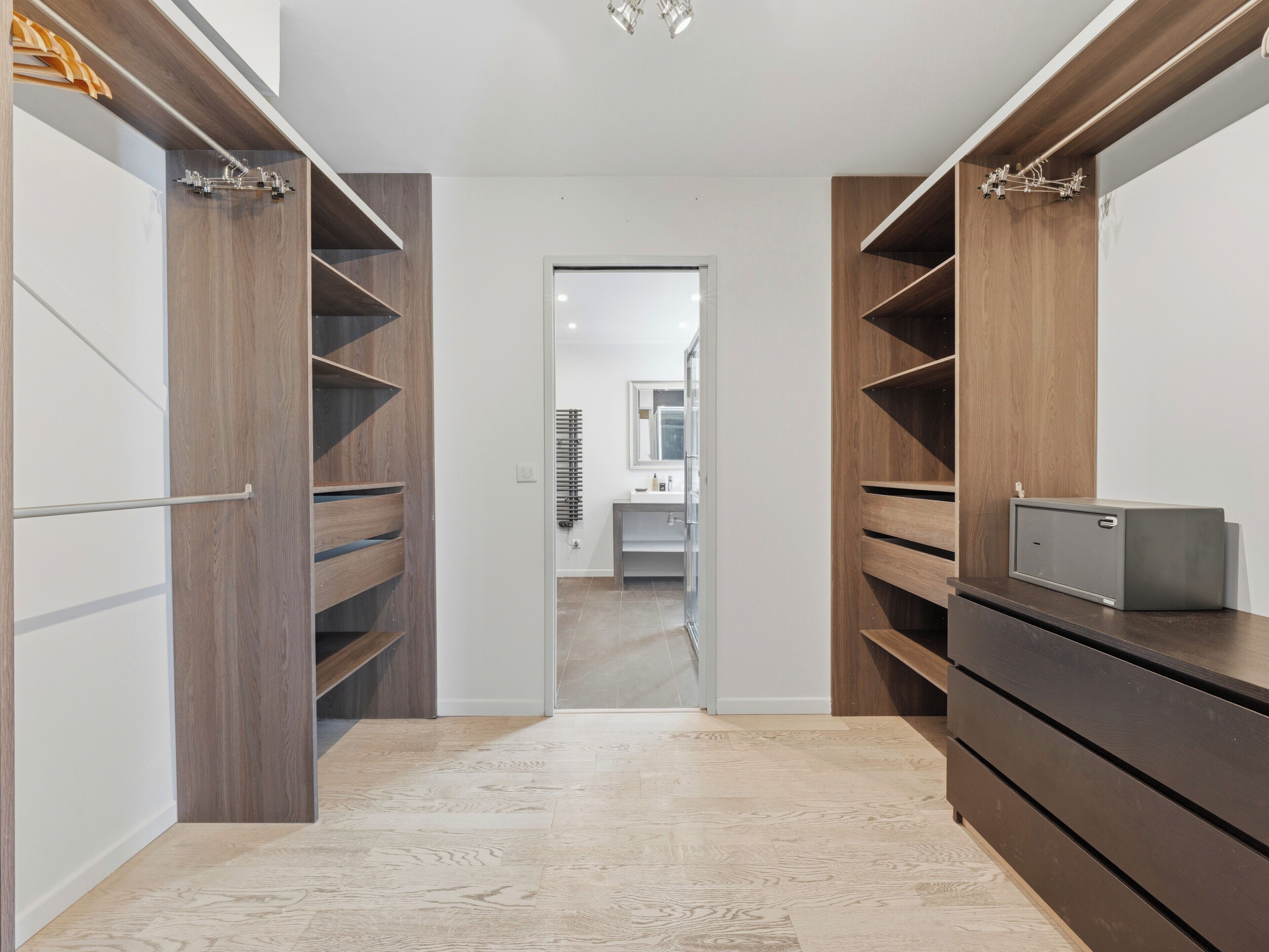 A walk-in closet with wooden shelving, a mirror, and a small safe.