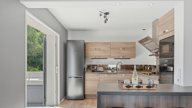 A modern kitchen with a large island, bar stools, and a built-in oven.