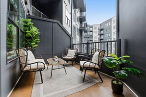 Ein Balkon mit Korbstühlen, einem kleinen Tisch und einem Blumentopf.