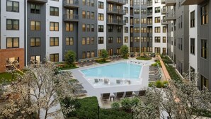 Ein modernes Apartmenthaus mit Innenhofpool, Balkonen und einem angelegten Garten.