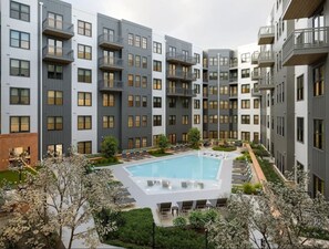 Ein modernes Apartmenthaus mit Innenhofpool, Balkonen und einem angelegten Garten.