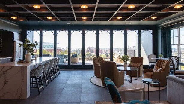 Ein modernes Interieur mit Bar, Sitzgelegenheiten und großen Fenstern mit Blick auf die Stadt.