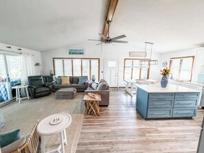 A spacious living area with a sofa, a dining table, a kitchen island, and a ceiling fan.