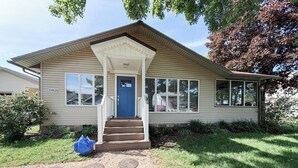 Einbungalow mit Veranda, einer blauen Tür und der Hausnummer 10828 an der Seite.