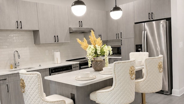 A modern kitchen with a central island, bar stools, pendant lighting, and stainless steel appliances. - The Royal Retreat in enchanting Frisco (Frisco)