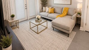 A living room with a sofa, coffee table, TV, and a ceiling fan. - The Royal Retreat in enchanting Frisco (Frisco)