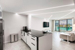 Una cocina moderna con cafetera integrada, una isla grande y un comedor con vistas a la ciudad.