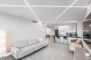Una cucina moderna con mobili bianchi, un'isola centrale e un'area pranzo con tavolo e sedie bianche.