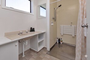 Ein Badezimmer mit Waschbecken, Spiegel, Dusche und Handtuchhalter.