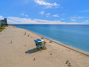 Ein Strand mit einer Rettungswache, blauem Himmel und ruhiger See.