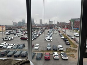A parking lot with multiple rows of parked cars and a view of a cityscape in the background. - Bright apartment within walking distance of college World Series and downtown (Omaha)