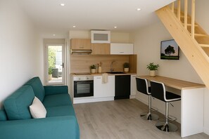 A compact kitchen with a built-in oven, a dining area with two bar stools, and a staircase. - Touraine-style cottage with private garden. (Esvres)