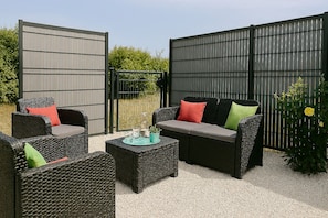 A patio area with wicker furniture, a glass-top table, and a metal fence. - Touraine-style cottage with private garden. (Esvres)