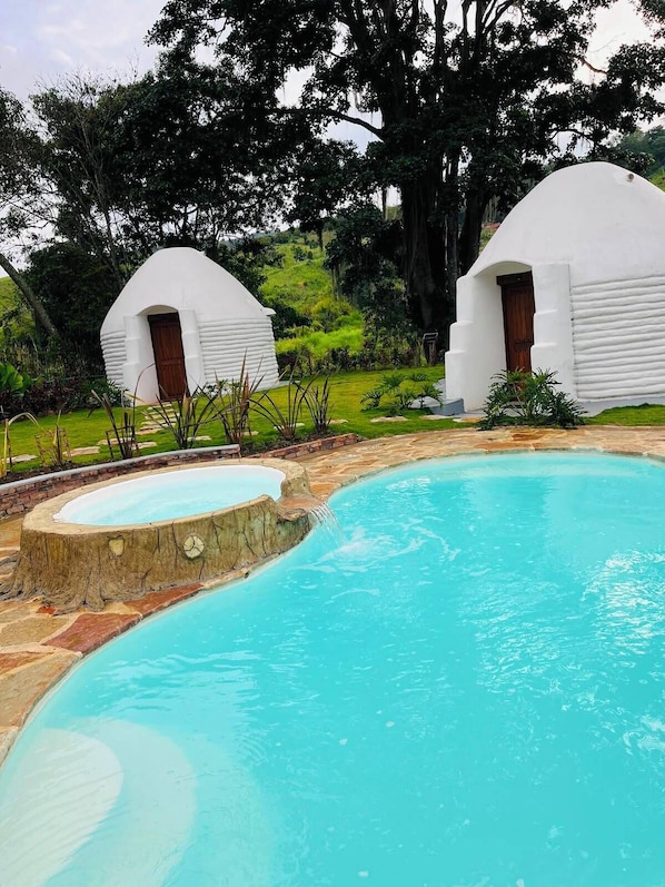 A pool with two white dome-shaped structures, surrounded by a landscaped garden.