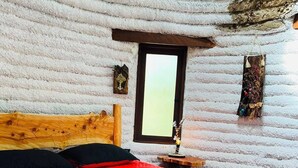 Une pièce avec un lit en bois, une fenêtre et une petite table avec une lampe.