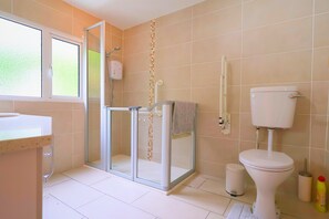 A bathroom with a toilet, a shower enclosure, a sink, and a window. - At entrance of Tollymore Park! Family sized house with large garden and parking (Newcastle)