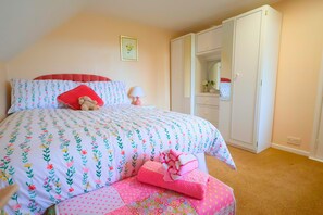 Een slaapkamer met een bed, een kledingkast, een nachtkastje en een lamp.