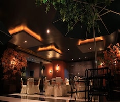 Un salón de banquetes con asientos escalonados, iluminación ambiental y plantas decorativas.