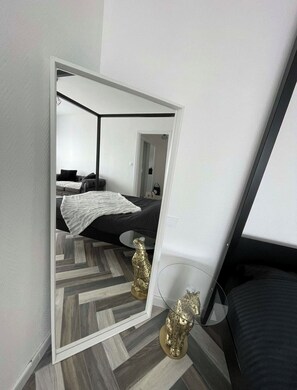 Ein Schlafzimmer mit einem Spiegelkleiderschrank, einem Bett, einem kleinen Tisch und zwei Leopardenstatuen.
