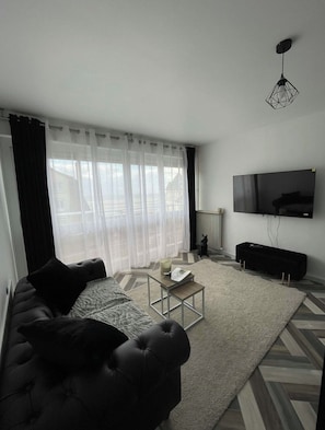Ein modernes Wohnzimmer mit Sofa, Couchtisch und Flachbildfernseher.