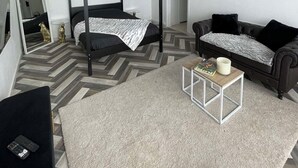Un dormitorio moderno con cama con dosel, un sofá, una mesita de centro y un espejo.