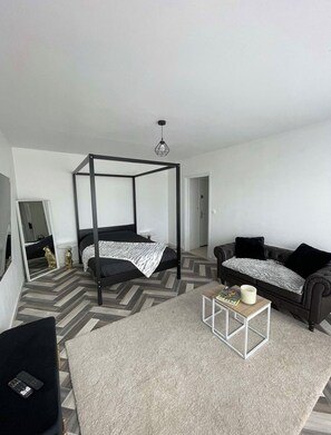Ein modernes Schlafzimmer mit einem Himmelbett, einer Couch, einem Couchtisch und einem Spiegel.