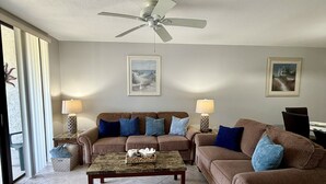 Ein Wohnzimmer mit Deckenventilator, zwei Sofas, einem Couchtisch und zwei Lampen.